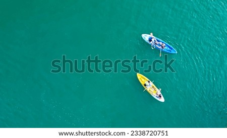 Aerial view of canoe boats in mountain river with turquoise water with rock cliffs. People kayaking, canoeing, and swimming in Kedung Jati Parang, Selopamioro, Imogiri, Bantul, Yogyakarta.