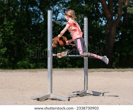 Girl jumping on hobby horse. Champion. Horse sport. Summer light. Green outdoor trees background. Child sport. Banner Royalty-Free Stock Photo #2338730903