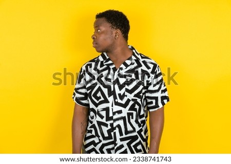 Close up side profile photo Young latin man wearing printed shirt over yellow background not smiling attentive listen concentrated