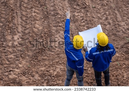 Land surveyor team standing working together at construction field consult study looking building location with floor plan Royalty-Free Stock Photo #2338742233