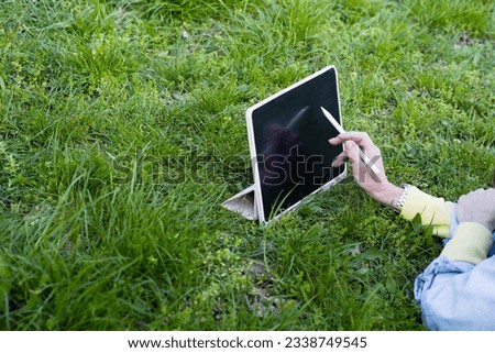 tablet in female hands on the grass