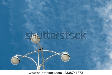 A lighting pole with round lamps against the sky.