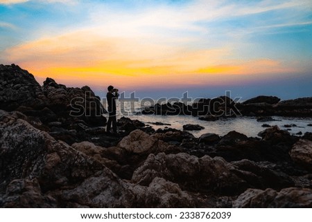 Sea ​​view during twilight This picture was taken from the beach. Expose the rocks and a young man standing on the rocks taking pictures and has a backdrop of sea and sky.