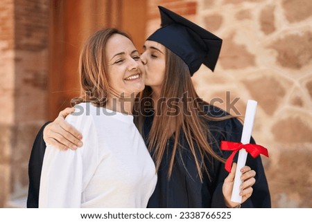 Two women mother and graduated daughter standing together at campus university Royalty-Free Stock Photo #2338766525