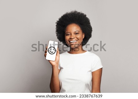 African amrerican woman showing modern smartphone with smile on display 