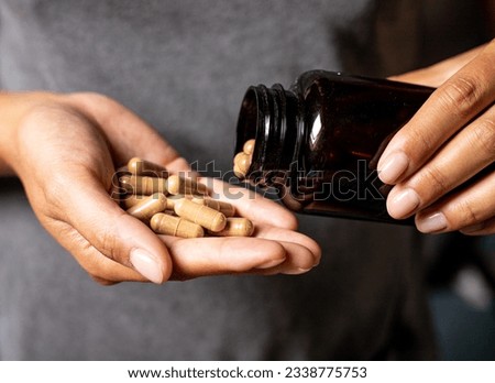 Ashwagandha capsules dosage, hand holding pills and vitamin jar, medical body and mind support Royalty-Free Stock Photo #2338775753