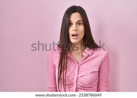 Young hispanic woman standing over pink background afraid and shocked with surprise and amazed expression, fear and excited face.  Royalty-Free Stock Photo #2338786049