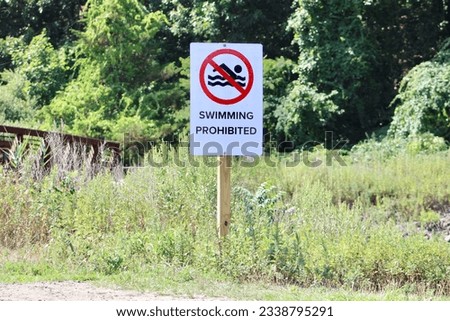 A sign on a wooden post that says "Swimming Prohibited".