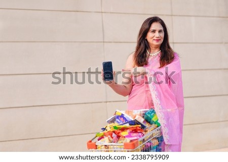 Young indian woman showing smartphone screen after shopping