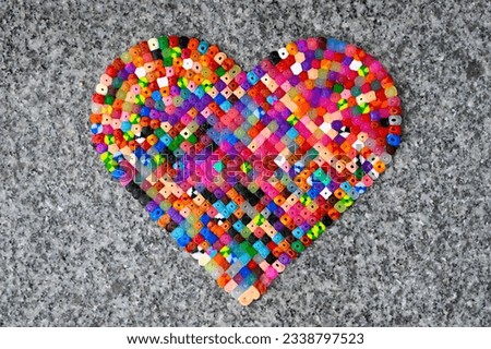 many colors motley heart made of ironing beads on a granite background
