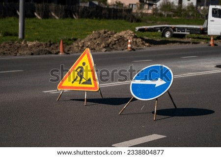 Blue and yellow-red safety signs warning about road works.The road is under construction or repair. Repair work in the middle of the carriageway, selective focus.