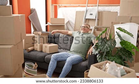 Middle age grey-haired man smiling confident sitting on sofa at new home