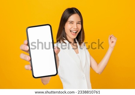 Beautiful Asian woman holding smartphone mockup of blank screen and smiling on yellow background. Royalty-Free Stock Photo #2338810761