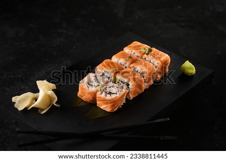 Japanese rolls sushi and seafood and vegetables on a dark background with chopsticks