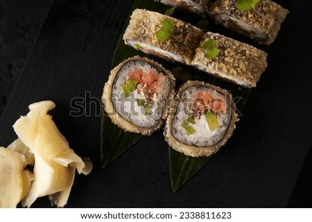 Japanese rolls sushi and seafood and vegetables on a dark background with chopsticks