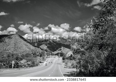 a photography of a highway with cars driving down it, there is a black and white photo of a highway with cars.