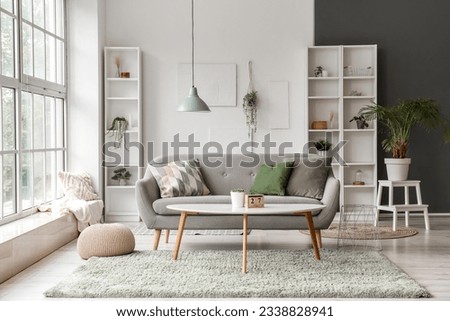 Interior of light living room with grey sofa, coffee table and big window Royalty-Free Stock Photo #2338828941