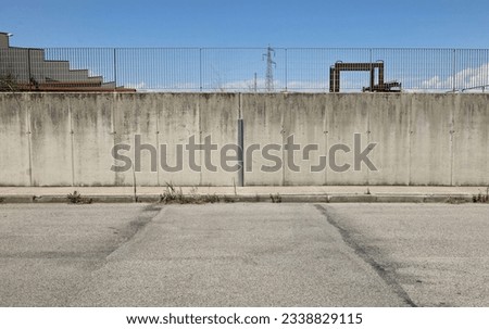 Surrounding wall made of concrete blocks with railing on top in the industrial area. Sidewalk and road in front. Background for copy space.