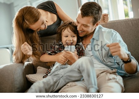 Young family using a smart phone while sitting on the couch in the living room Royalty-Free Stock Photo #2338830127