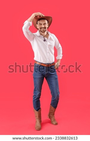 Handsome cowboy on red background Royalty-Free Stock Photo #2338832613