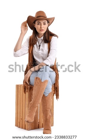 Beautiful cowgirl sitting on white background Royalty-Free Stock Photo #2338833277