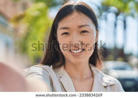 Chinese woman smiling confident making selfie by camera at park