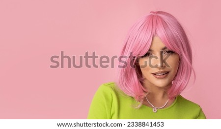 Cute young woman with pink hair and bright green dress on isolated pink background.