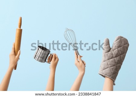 Female hands with baking utensils on blue background Royalty-Free Stock Photo #2338841847