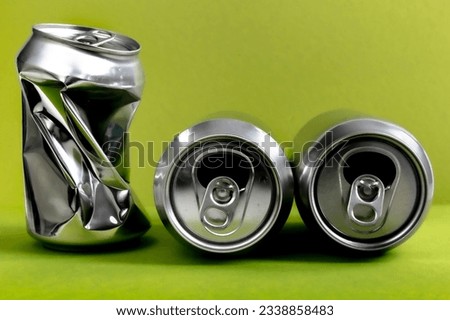 Three aluminum crushed cans for beverage. Still-life picture of some metallic containers isolated on green background.