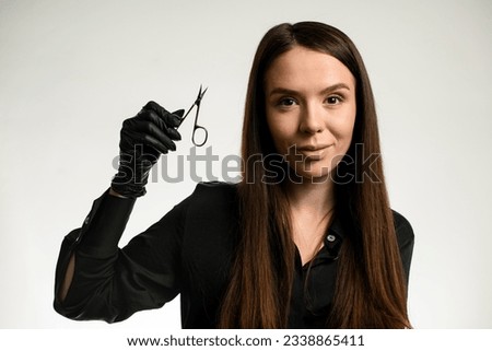 Darkhair attractive woman manicure master or nail care beautician holding sharp manicure scissors. Nail cutter. White background Royalty-Free Stock Photo #2338865411