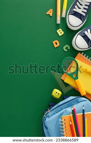 Essential schooltime supplies theme. Top view vertical photo of stationery, child's rucksack, shoes, letters and numbers on green background with empty space for promo or text