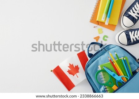 Preparing for the school season in Canada. Top view shot of canadian flag, blue rucksack, notepad, pencils, magnifier, scissors, shoes, markers, letters on white background with space for ads or text