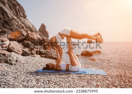 Woman sea yoga. Two happy women practicing yoga on the beach with ocean and rock mountains. Motivation and inspirational fit and exercising. Healthy lifestyle outdoors in nature, fitness concept.