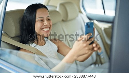 Young beautiful hispanic woman passenger make selfie by smartphone sitting on car at street