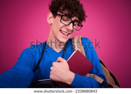 Funny student prepares for exams and goes shopping. The guy poses on a pink background.