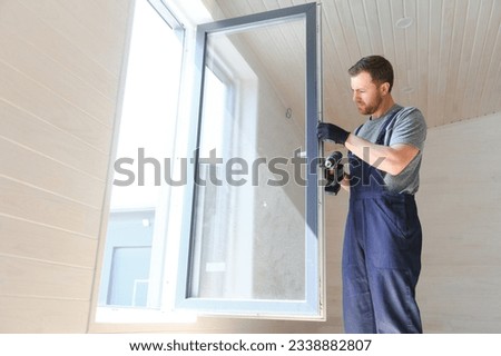 Construction worker installing new window in house. Royalty-Free Stock Photo #2338882807