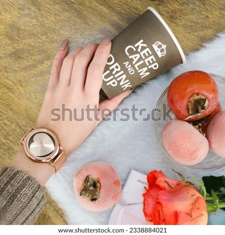 Stylish watch on a hand; against the background of cup with phrase "Keep calm and drink up"