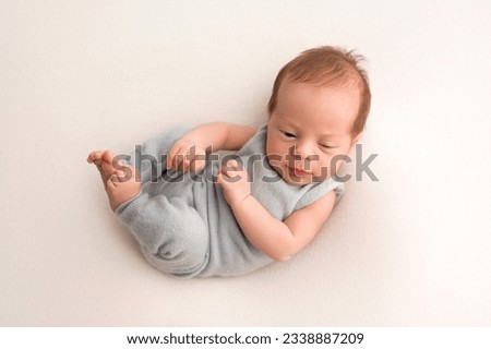 A cute newborn baby boy lies in a blue overalls in the first days of life. On a white background. Professional macro photography. Portrait. Royalty-Free Stock Photo #2338887209
