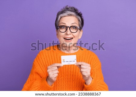 Photo of funky excited woman dressed orange sweater eyewear rising credit card isolated violet color background