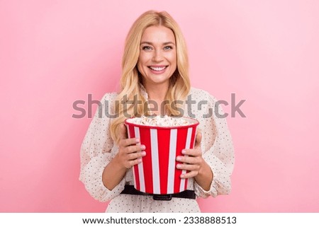 Photo portrait of cheerful positive friendly young lady hold huge bucket pop corn watching new tv show isolated on pink color background