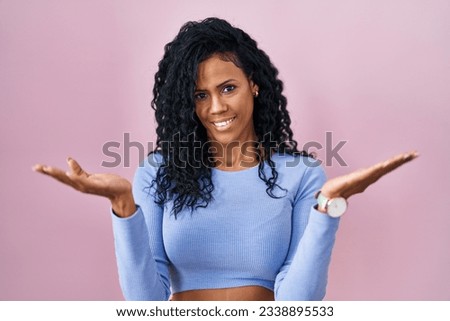 Middle age hispanic woman standing over pink background smiling cheerful offering hands giving assistance and acceptance. 