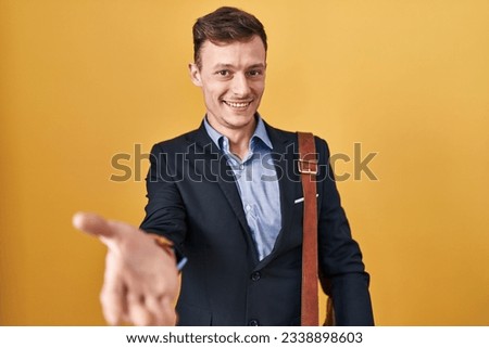 Caucasian business man over yellow background smiling cheerful offering palm hand giving assistance and acceptance. 
