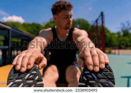 young muscular sportsman bodybuilder doing abs exercises during street workout sports ground close-up Royalty-Free Stock Photo #2338903495
