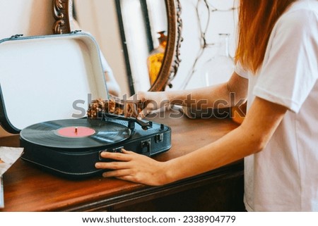 A modern teenage girl with dyed hair turns on a retro record player, meeting modern with retro Royalty-Free Stock Photo #2338904779