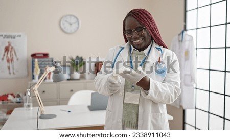 African woman with braided hair doctor putting gloves for safety at clinic