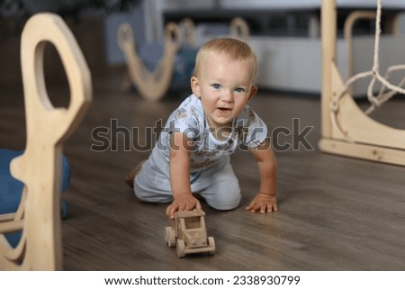 Child plays with wooden car in interior, play area