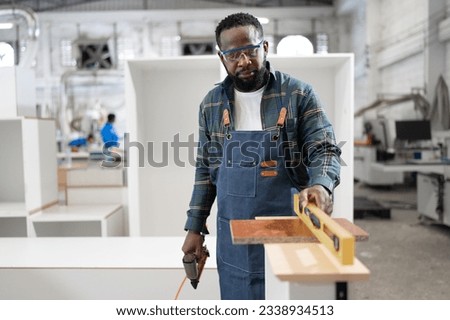 African American carpenter use Precision level to wood at wood factory