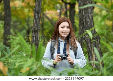 A young woman wearing a camera and backpack traveling to tourist attractions with traditional Korean houses and taking pictures