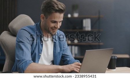 Young Handsome Businessman, Freelancer is chatting on Laptop, working Online. Young Successful Man is working from Home Office, surfing, sharing Positive Emotions. Online Job, Working Indoor.