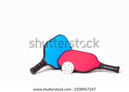 Couples Pickleball....Pink and Blue Pickleball paddles with white Pickleball on a white background. Royalty-Free Stock Photo #2338967247